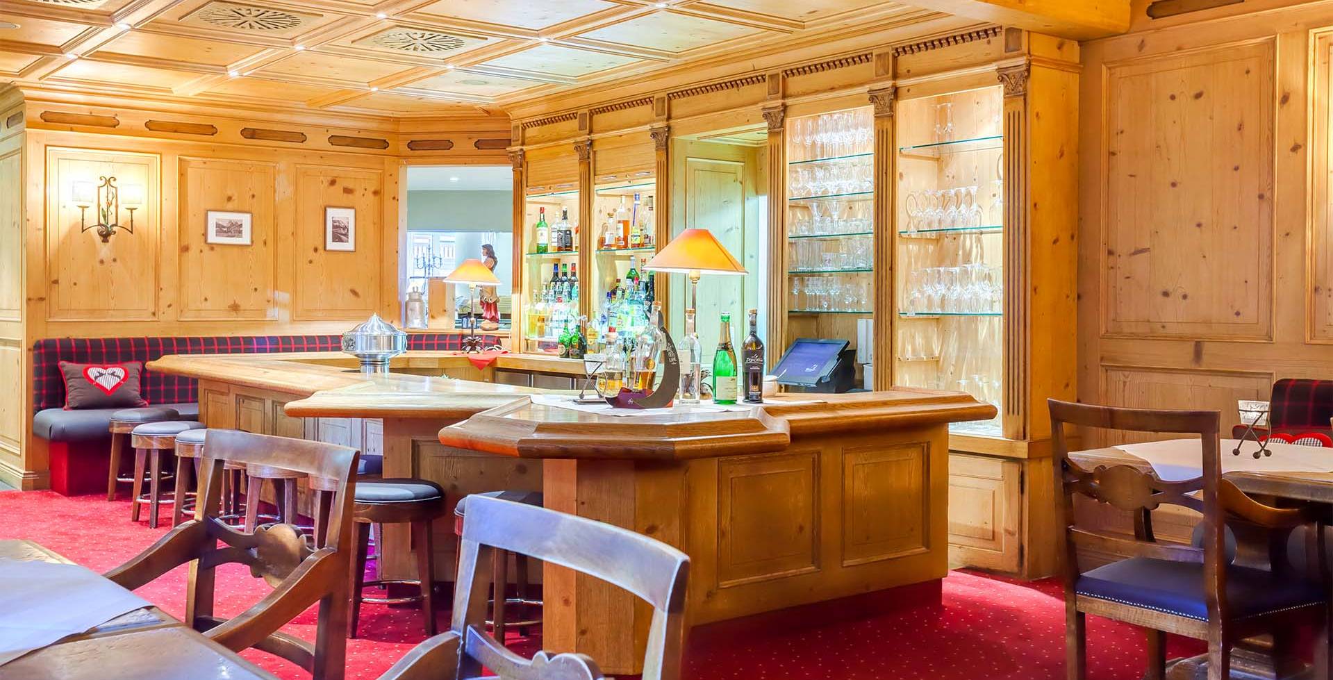 Die Räumlichkeiten der Kaminbar mit Holzvertäfelungen, Tischecken und Holztheke schaffen eine gemütliche Atmosphäre.