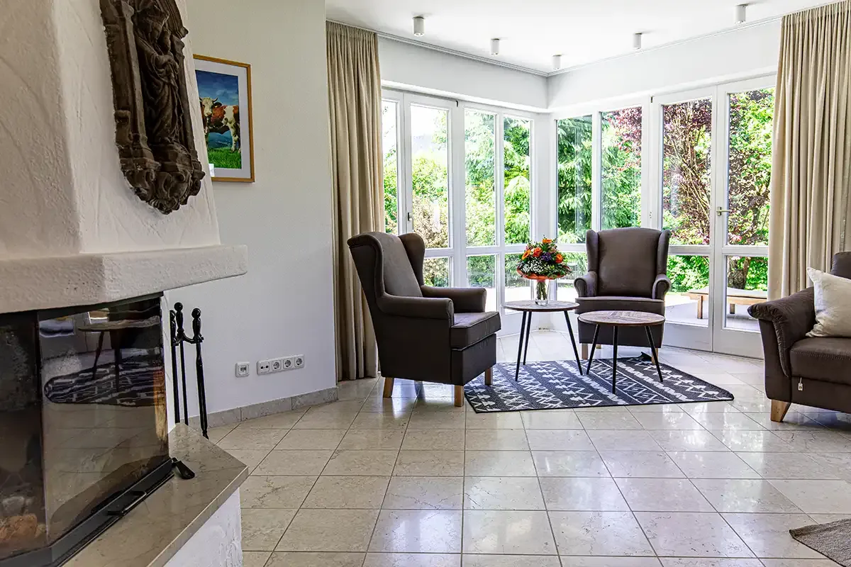 Wohnbereich im Chalet mit hellen Fliesen und Kaminecke zum Aufwärmen, sowie einer gemütlichen Sitzecke an einer Fensterfront