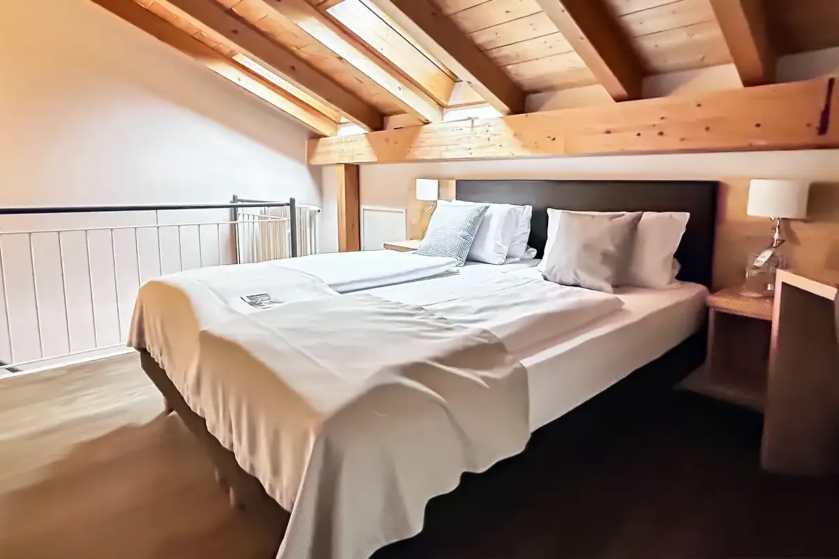 Großes modernes Doppelbett im Dachgeschoss mit hohen Decken aus Holz für einen gemütlichen Aufenthalt.