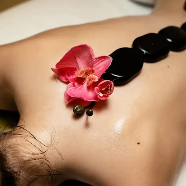 Eine Person liegt auf dem Bauch und genießt eine Hot-Stone-Massage im Berghotel Hammersbach.