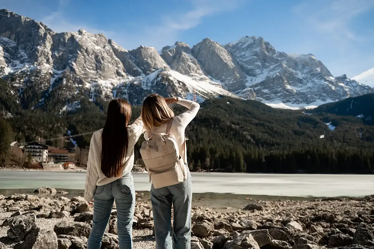 Zwei Frauen stehen am Eibsee und blicken auf die malerische Alpenlandschaft im Hintergrund.