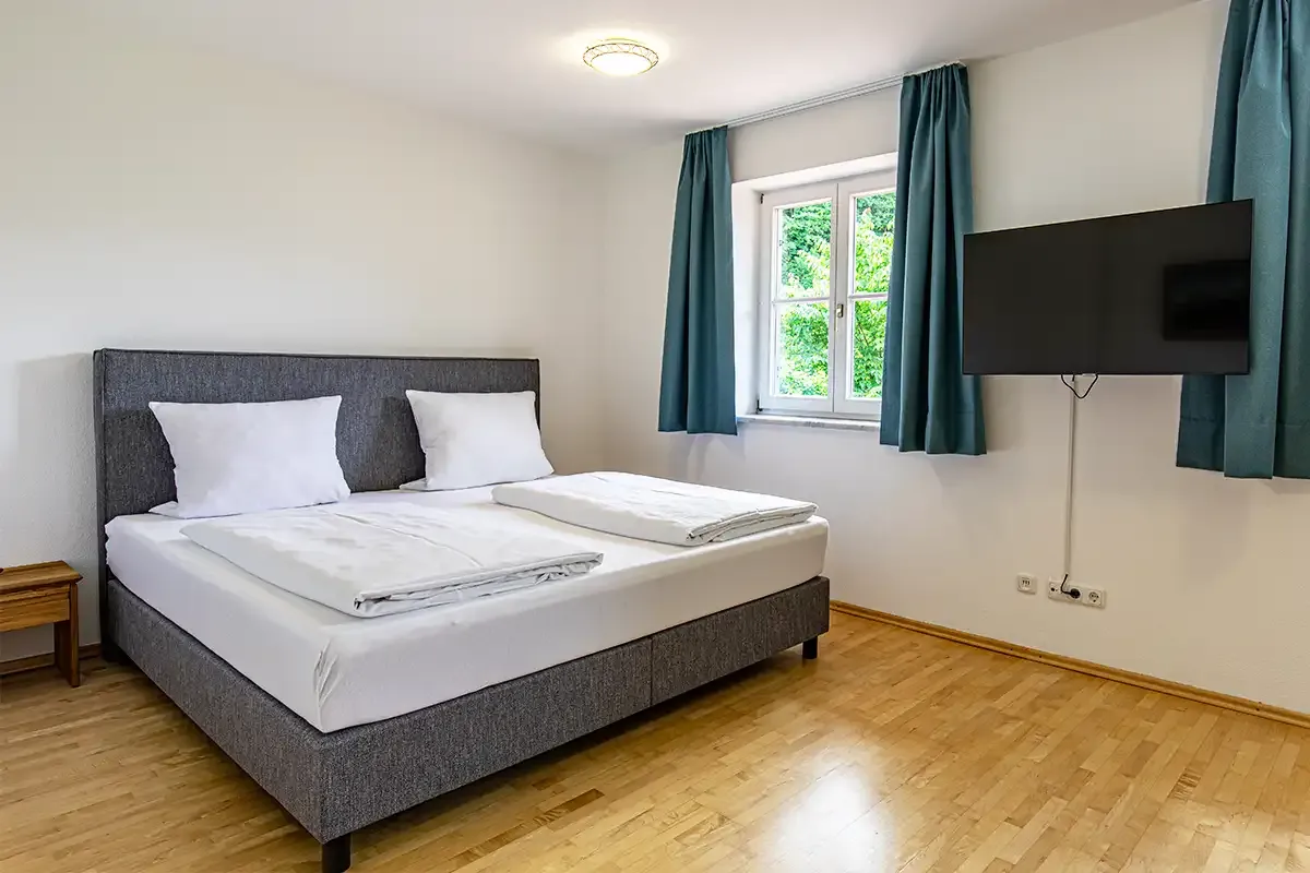Helles Schlafzimmer mit großem Doppelbett, TV an der Wand und ausreichend Platz zum Erholen.