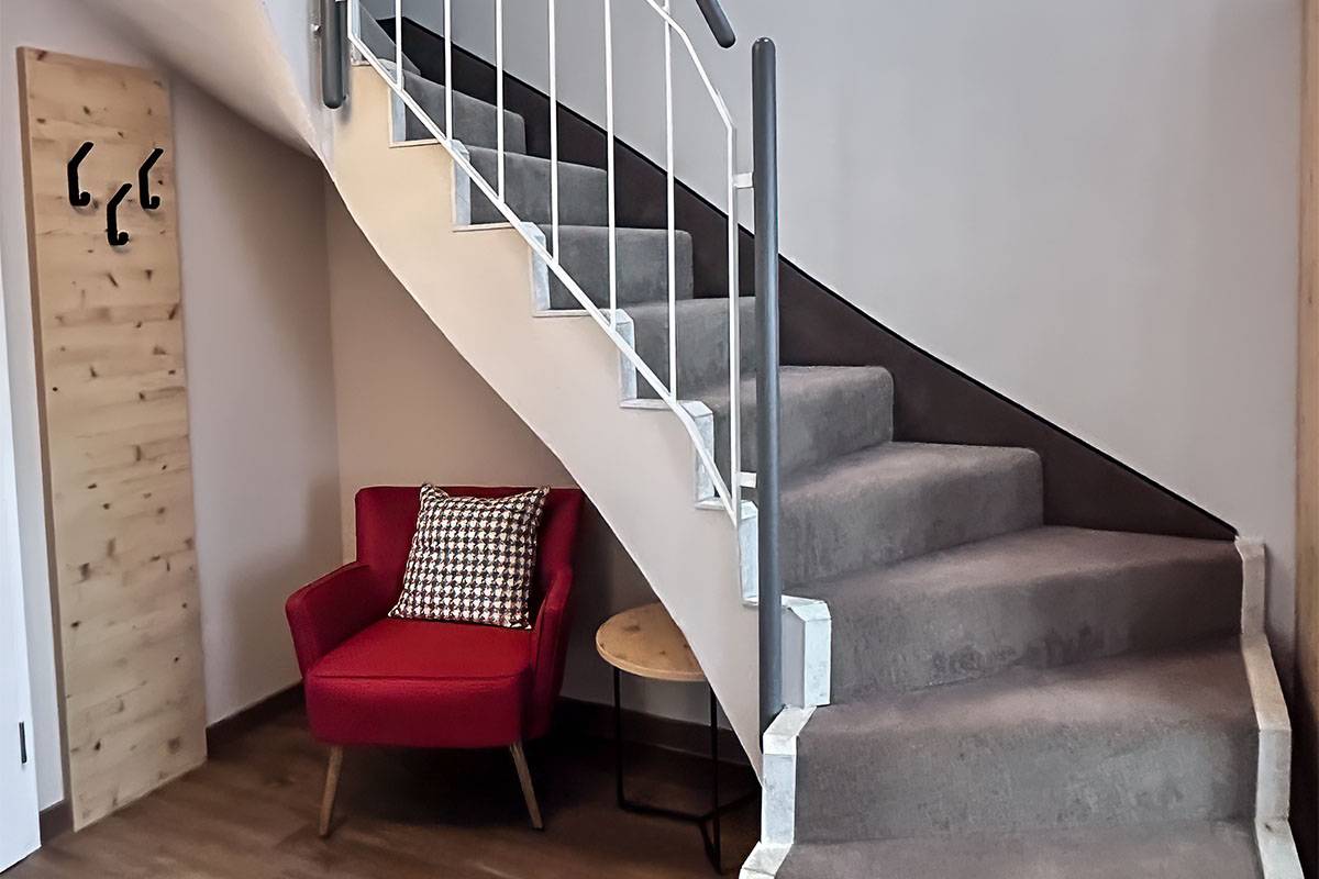 Moderne Treppe mit Teppich ausgelegt, darunter eine Garderobe mit Sitzmöglichkeit.