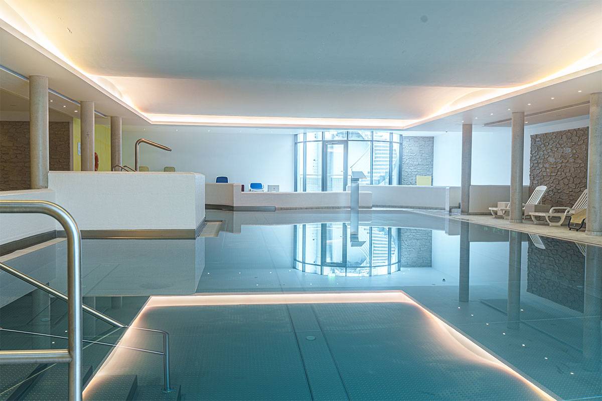 Poolbereich mit angenehmer Beleuchtung und Liegemöglichkeiten zum erholen im Berghotel Hammersbach.