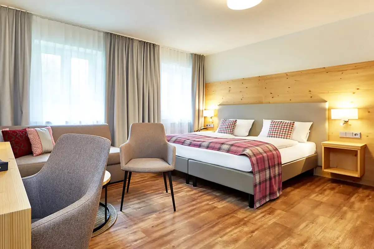 Modernes Familienzimmer mit großen Doppelbett, Schlafsofa, Schreibtisch und Sitzmöglichkeiten im Berghotel Hammersbach.