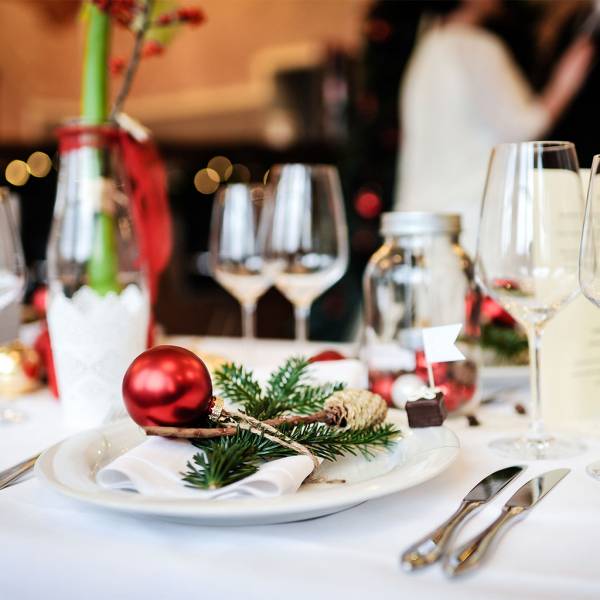 Feierlich eingedeckter Tisch mit Tannengrün und roter Weihnachtskugel im Berghotel Hammersbach.