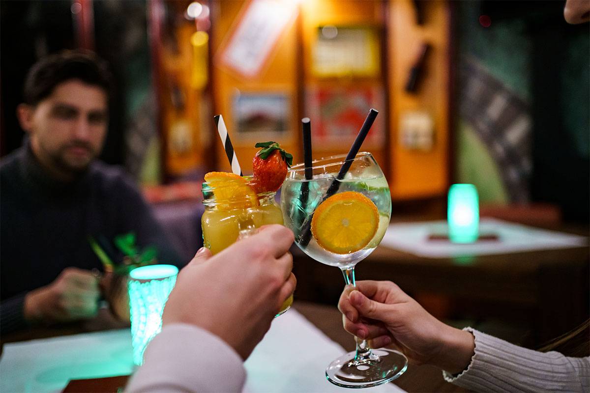 Zwei Personen stoßen in der gemütlichen Bar Endstation im Berghotel Hammersbach mit einem Cocktail an.