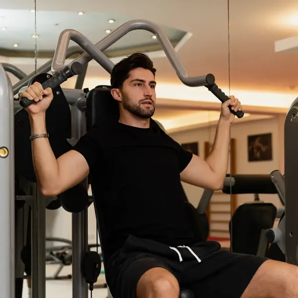 Mann sitzt auf einen Trainingsgerät im Berghotel Hammersbach und macht Sport.