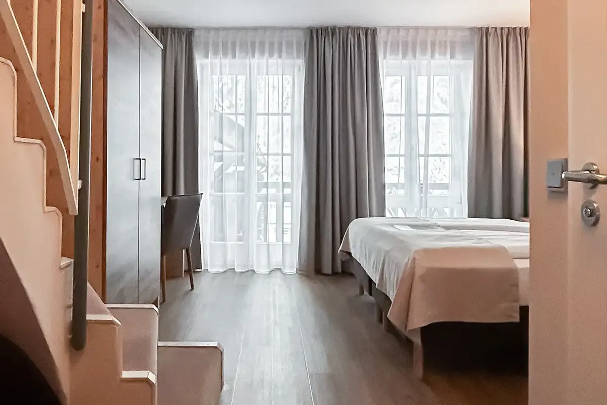 Familienzimmer im Berghotel Hammersbach mit Fensterfront, Kleiderschrank und großen Doppelbett.