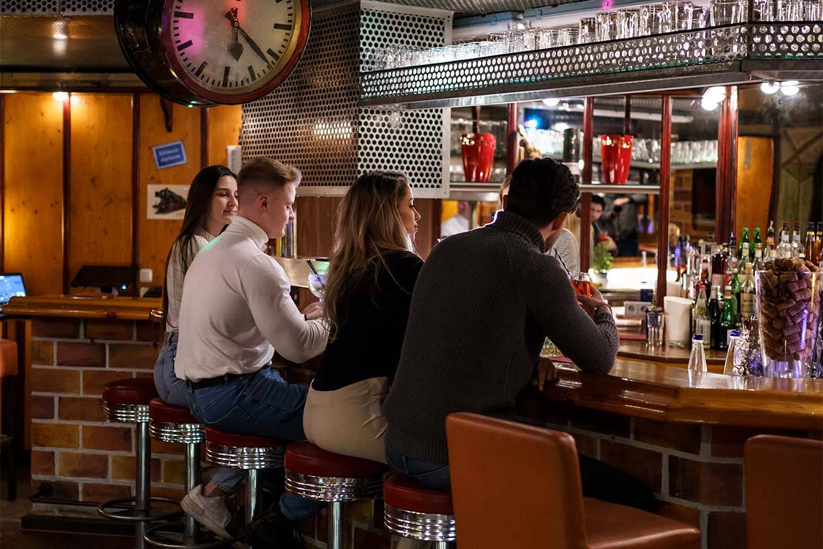Vier Personen sitzen an der Theke in der Endstation Bar und lassen den Tag mit Cocktails ausklingen.