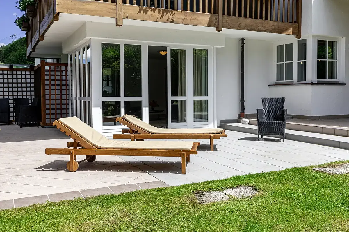 Holzliegen auf einer gepflasterten Terrasse vor dem privaten Chalet mit ausreichend Platz zum Sonnen.