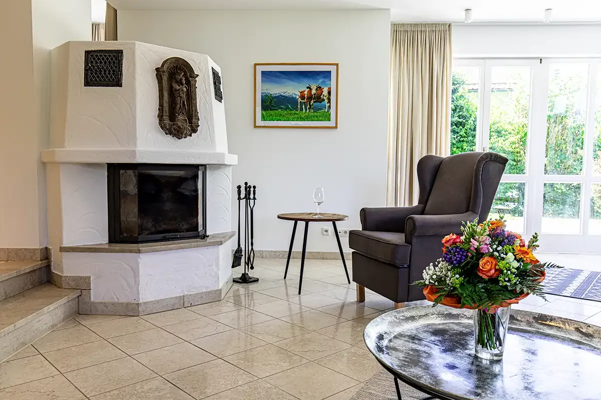 Kaminecke im Wohnbereich des Chalets mit Sessel, Beistelltisch und einem Glas Wein.