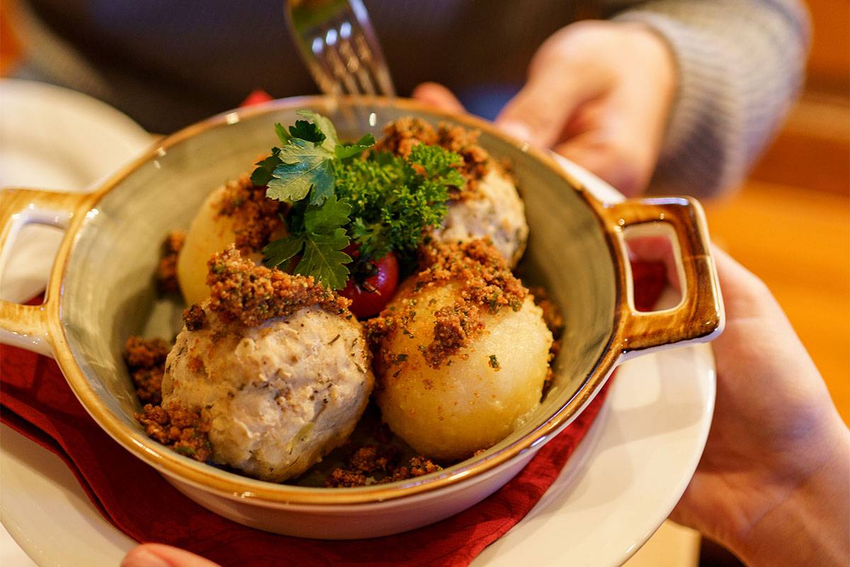 Schüssel mit vier Reibeknödeln nach bayerischer Art, verfeinert mit einer Gewürzmischung als Topping.