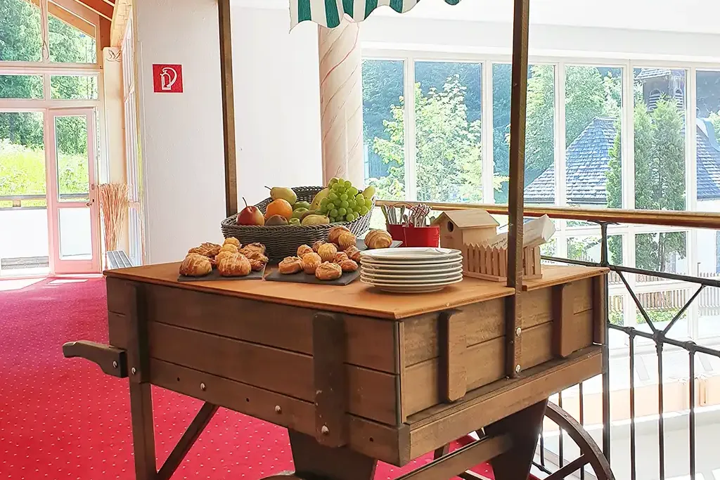 Holzbar auf Rädern, auf der Snacks wie Obst und Gebäck platziert sind.