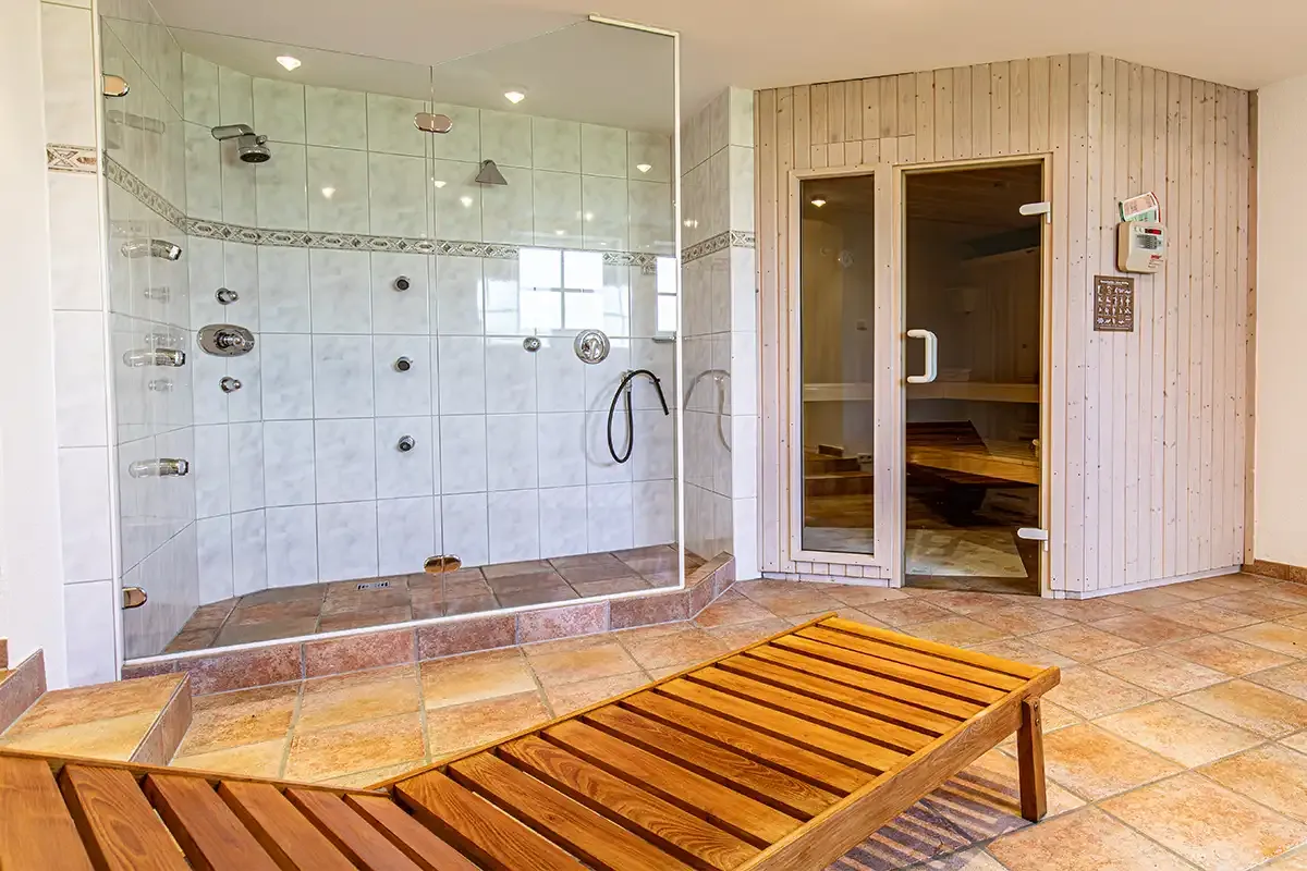 Privater Wellnessbereich im Chalet mit Sauna und großem Duschbereich sowie einer Holzliege zum Entspannen.