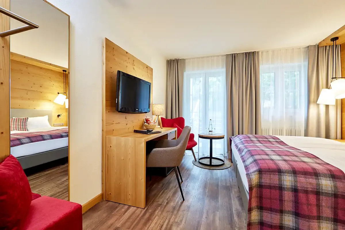 Helles Doppelzimmer mit Fensterfront, Blick in die Natur und gemütlichem Komfort im Hotelzimmer.