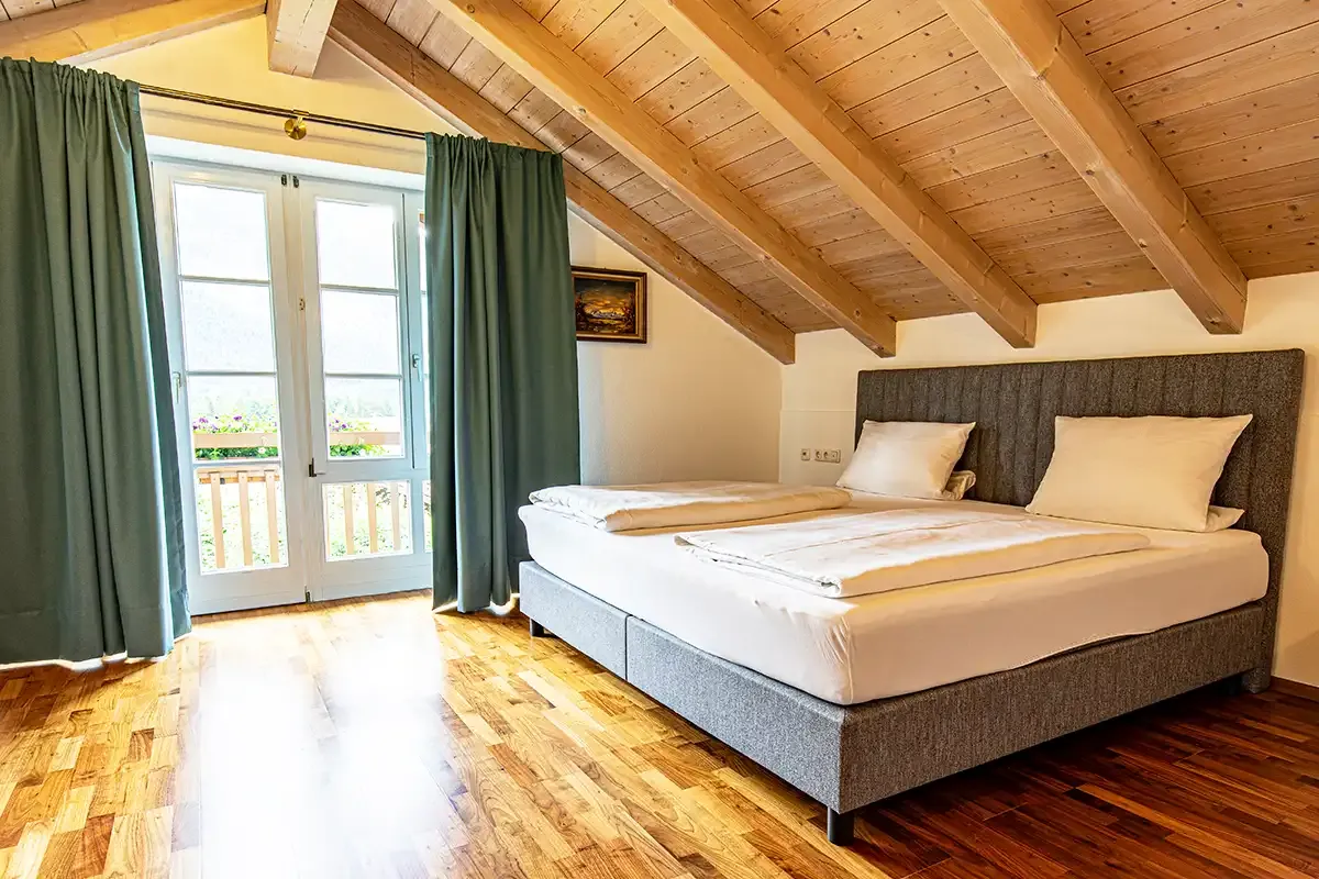 Helles Schlafzimmer im Dachgeschoss mit einem komfortablen Doppelbett und lichtdurchflutenden Fenstern im Chalet.