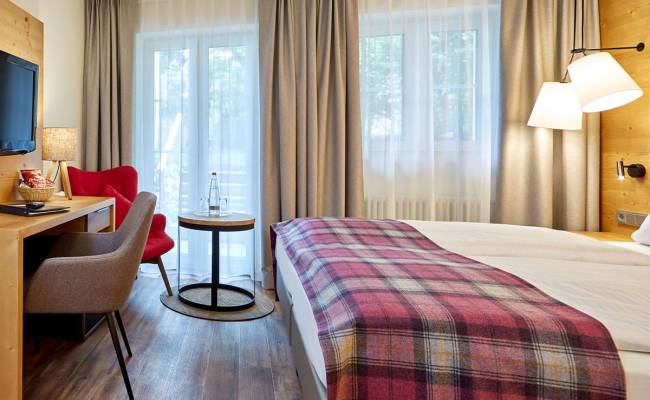 Helles Doppelzimmer mit großem Doppelbett, Schreibtisch und Sitzecke, ideal zum Entspannen.