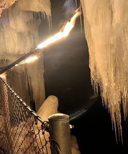 Eine Gruppe von Menschen läuft hintereinander an einem Felsen vorbei und hält Fackeln in der Hand.