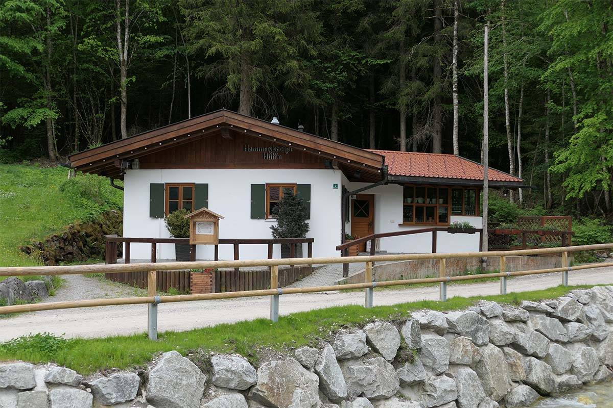 Außenansicht der bayerischen Hammersbach Hütte in den Alpen, umgeben von grünen Bäumen.