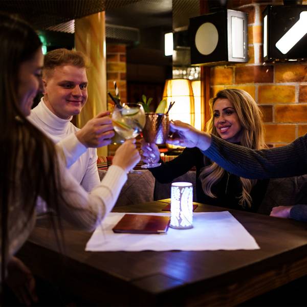 Eine Gruppe sitzt gemeinsam entspannt an einem Tisch und stößt mit Cocktails auf den Tag an.