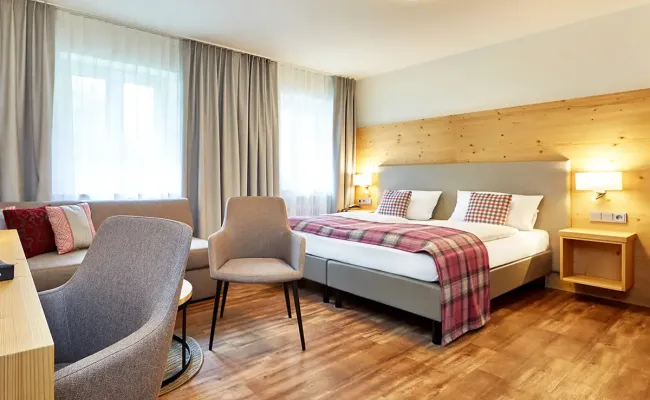 Modernes und helles Familienzimmer mit großen Doppelbett, Schreibtisch und Schlafsofa im Berghotel Hammersbach.