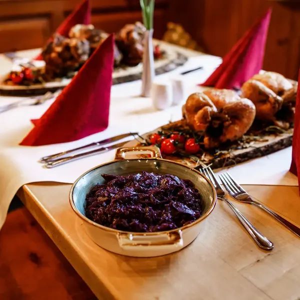 Ein festlich gedeckter Tisch mit knuspriger Schweinshaxe und Rotkohl im Berghotel Hammersbach.