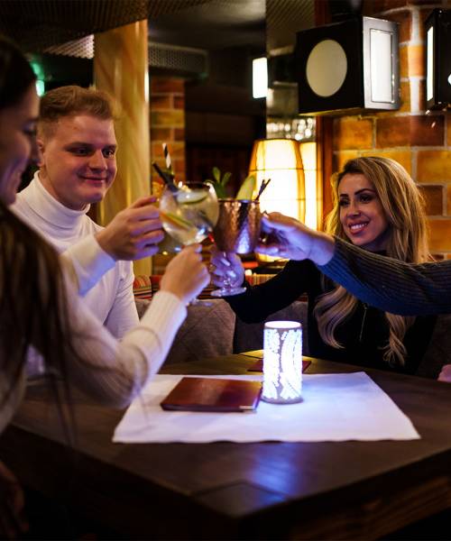 Eine Gruppe sitzt an einem Tisch in der Bar Endstation und stößt mit bunten Getränken an.