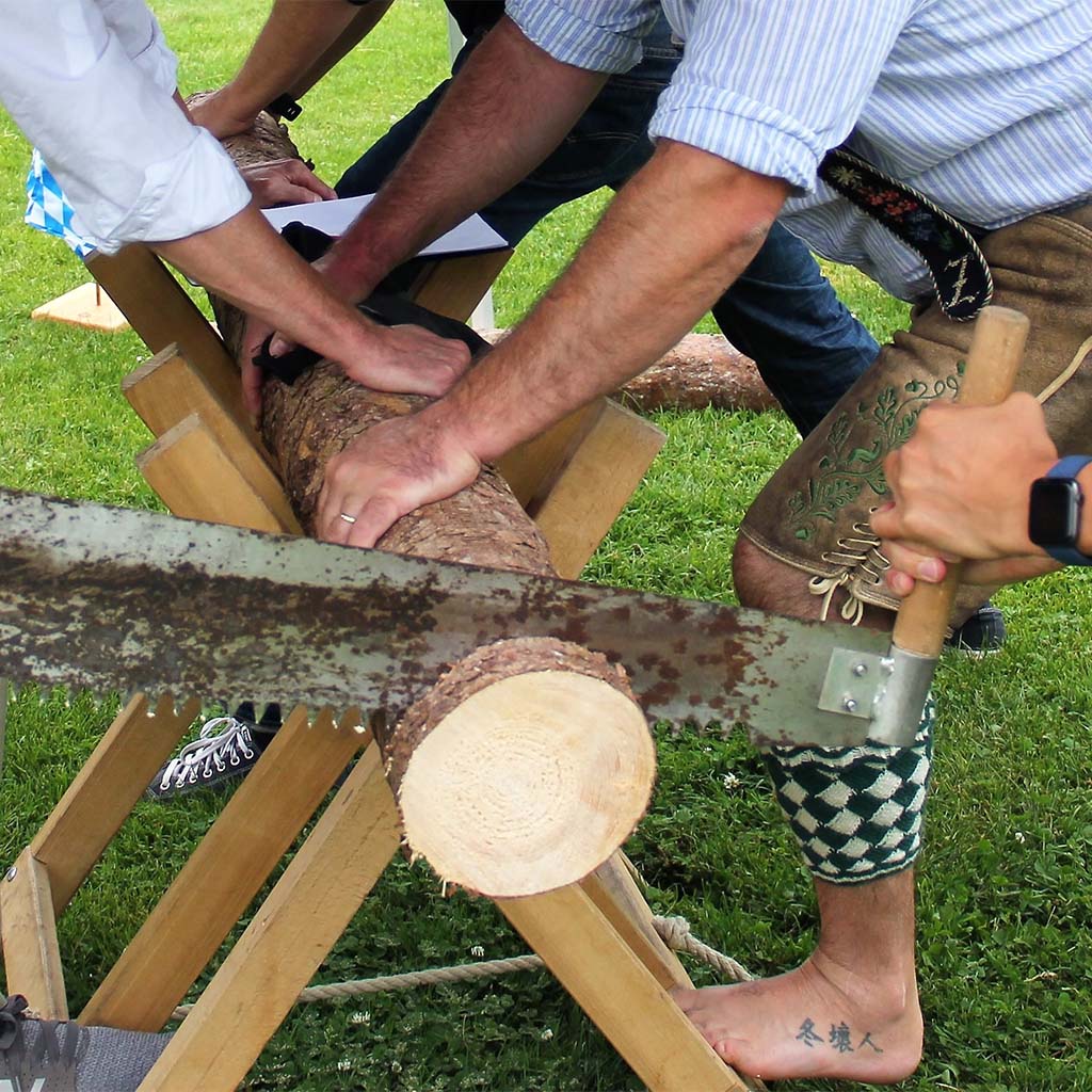 Männer halten einen Holzstamm in einer Vorrichtung, während das Stück Holz gesägt wird.