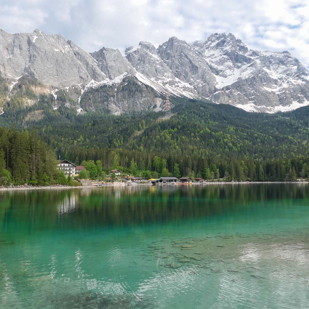 Blick auf den klaren, blauen Eibsee. Im Hintergrund das Bergpanorama der Alpen.